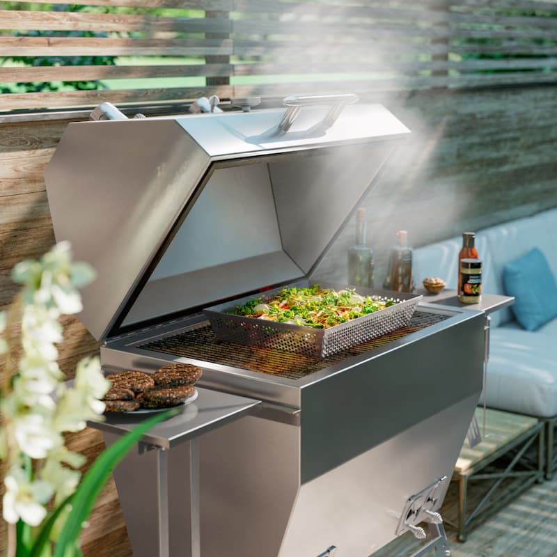 Silver Rocket stainless steel grill with the lid open, cooking vegetables over charcoal with smoke rising from the grill.